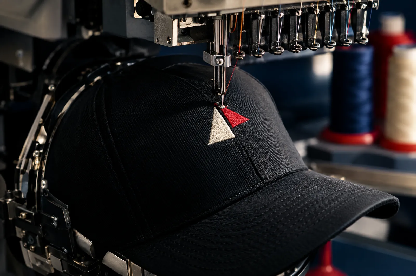 Gorra negra montada en el bastidor de gorra de una bordadora industrial